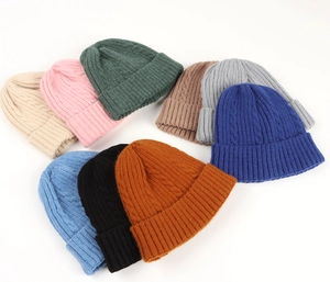Flat lay of nine colorful cable knit beanie hats showcasing various winter color options