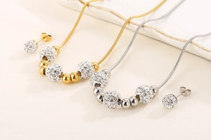 Détail d'un ensemble de bijoux or et argent avec perles de cristal et sphères d'acier sur plateau