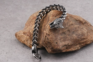 Detail of punk wolf head clasp on braided leather bracelet for men on rustic stone