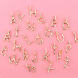 Vue à plat de 26 pendentifs alphabet en métal doré sertis de zircons cubiques blancs