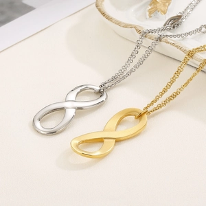 Golden and silver infinity symbol necklace set on a white ceramic display tray