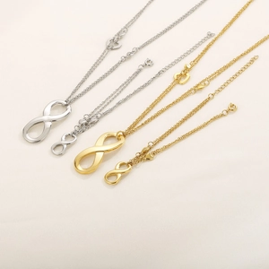Minimalist gold and silver infinity symbol necklaces and bracelets set on beige fabric