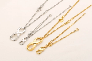 Detail of gold and silver infinity necklaces with heart charms on beige fabric