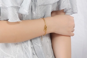 Close-up of gold infinity symbol bracelet with lobster clasp on a woman's wrist