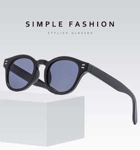 Detail view of round frame sunglasses with silver dots on light gray pedestal