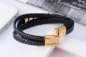 Détail du bracelet multicouche en cuir tressé noir avec fermoir magnétique doré poli