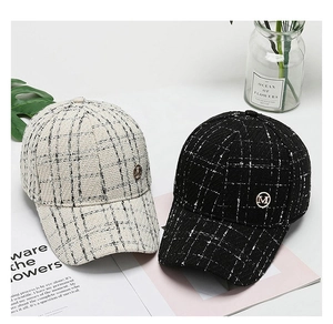 Detail of classic black and white tweed baseball caps with metallic M logo emblem