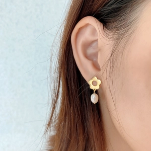 Close-up of a 925 sterling silver flower stud earring with a drop pearl on a model