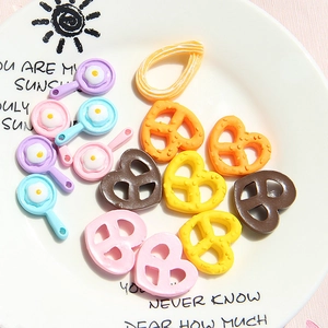 Macro shot of colorful resin miniature fried egg pans and pretzels craft accessories