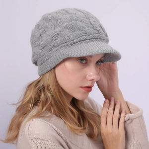 Detalle de gorra de punto trenzado gris claro con visera para mujer en invierno frío