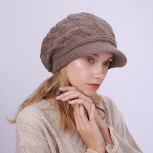 Detalle del tejido de trenzas de una gorra de lana marrón con visera para mujer