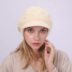 Vista frontal de una boina de punto trenzado color crema con visera corta para mujer