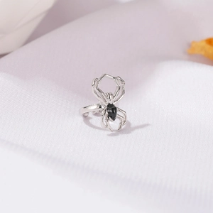Detailed close-up of a silver gothic spider ear cuff with black enamel on fabric