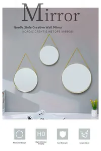 Close-up of Nordic round gold metal mirrors in three sizes hanging on a light gray wall