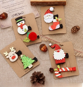 Detail of festive Christmas hair clips featuring reindeer and Santa on kraft paper cards