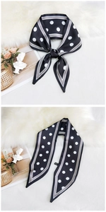 Close-up of elegant black and white polka dot silk scarf tied on a stylish white desk