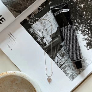 Close-up of heart-shaped silver necklace on lifestyle props and magazine background