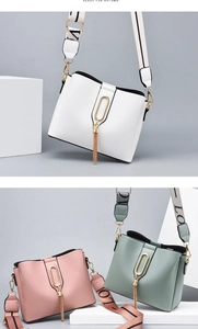 Detail of trendy bucket bag showing wide fabric strap with LOVE print and metal tassel