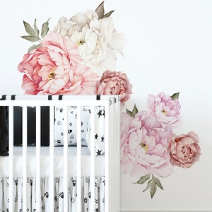 Watercolor peony wall stickers in pink and beige shades over a white baby crib