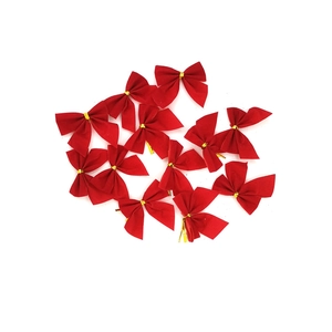 Close-up of small red decorative Christmas bows with golden twist ties on white background
