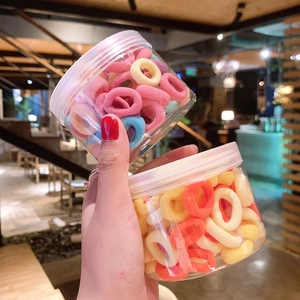 Close-up of colorful elastic hair bands packed in a transparent plastic jar container