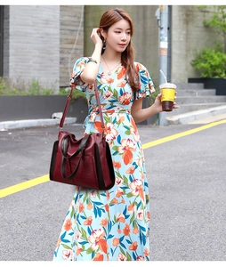 Outdoor shot of a deep red leather handbag carried by a model on a city street