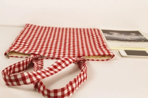 Detail of red gingham laptop sleeve with zip closure and sturdy cotton handles