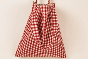 Detail view of red gingham crossbody bag with zipper closure and double handle strap
