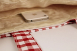 Interior view of the red plaid canvas bag featuring a smooth zipper and storage pocket