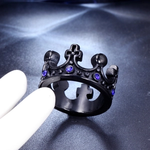 Macro shot of black crown ring with blue gems and cross details on dark leather