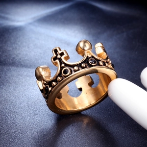 Detailed macro view of golden crown ring with black gemstones and cross symbol