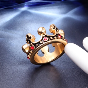 Macro shot of gold crown ring with red gemstone on a dark textured surface