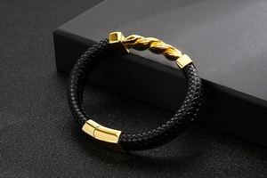 Detail of black braided leather bracelet with a polished gold magnetic metal clasp