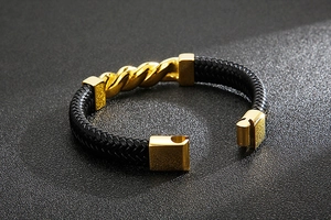Detail of black braided leather bracelet with golden stainless steel twisted buckle