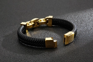 Close-up of men's braided leather bracelet with golden metal H-shaped accents
