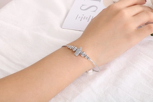Silbernes Edelstahl-Perlenarmband mit strukturiertem Metallanhänger und Perlen am Handgelenk
