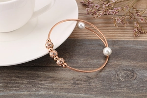 Detail of rose gold braided steel wire bracelet with pearls and zircon beads