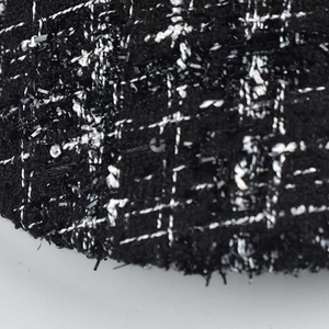 Close-up of black and white tweed fabric with silver metallic threads and sequins