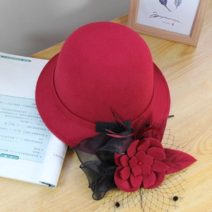 Detailed view of red wool felt pillbox hat featuring floral mesh and feather accents