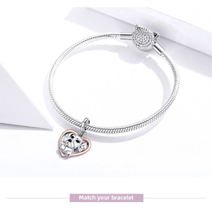 Detailed macro of a dual-tone S925 silver dog heart charm on a classic snake chain bracelet