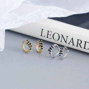 Detail shot of small silver and gold hoop earrings with black zircon stones