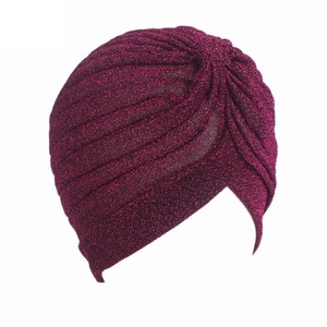 Detailed view of the purple glitter turban hat with metallic pleated texture and cross design