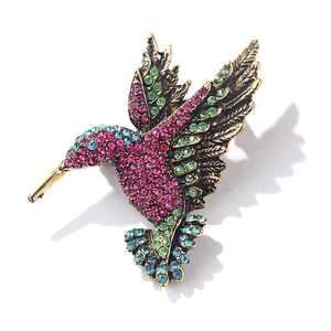 Vintage gold hummingbird brooch featuring pink green and blue crystals on white background