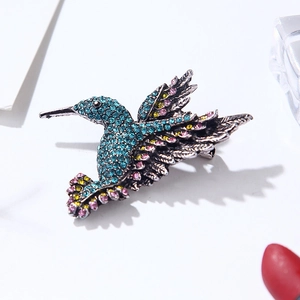 Detailed view of hummingbird brooch with blue crystals on vintage silver alloy base
