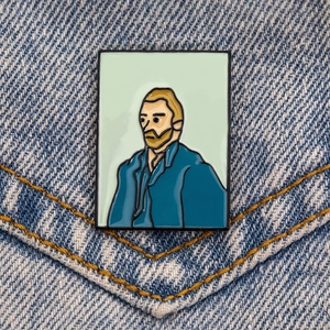 Détail du pin's en émail Van Gogh fixé sur une poche en jean bleu avec coutures jaunes