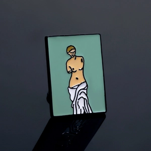 Vue détaillée d'un pin's en émail avec un dessin de la Vénus de Milo sur fond sombre
