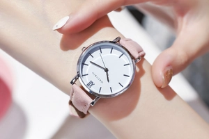 Makroaufnahme von rosa Lederarmband und silbernem Gehäuse mit weißem römischem Zifferblatt