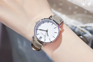 Minimale Quarzuhr mit silbernem Rundgehäuse, weißem Zifferblatt und grauem Wildlederarmband