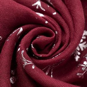 Macro detail of wine red Christmas scarf with shiny silver snowflake foil print texture