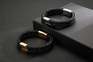 Detail of double-layer black braided leather bracelets with gold and silver magnetic clasps